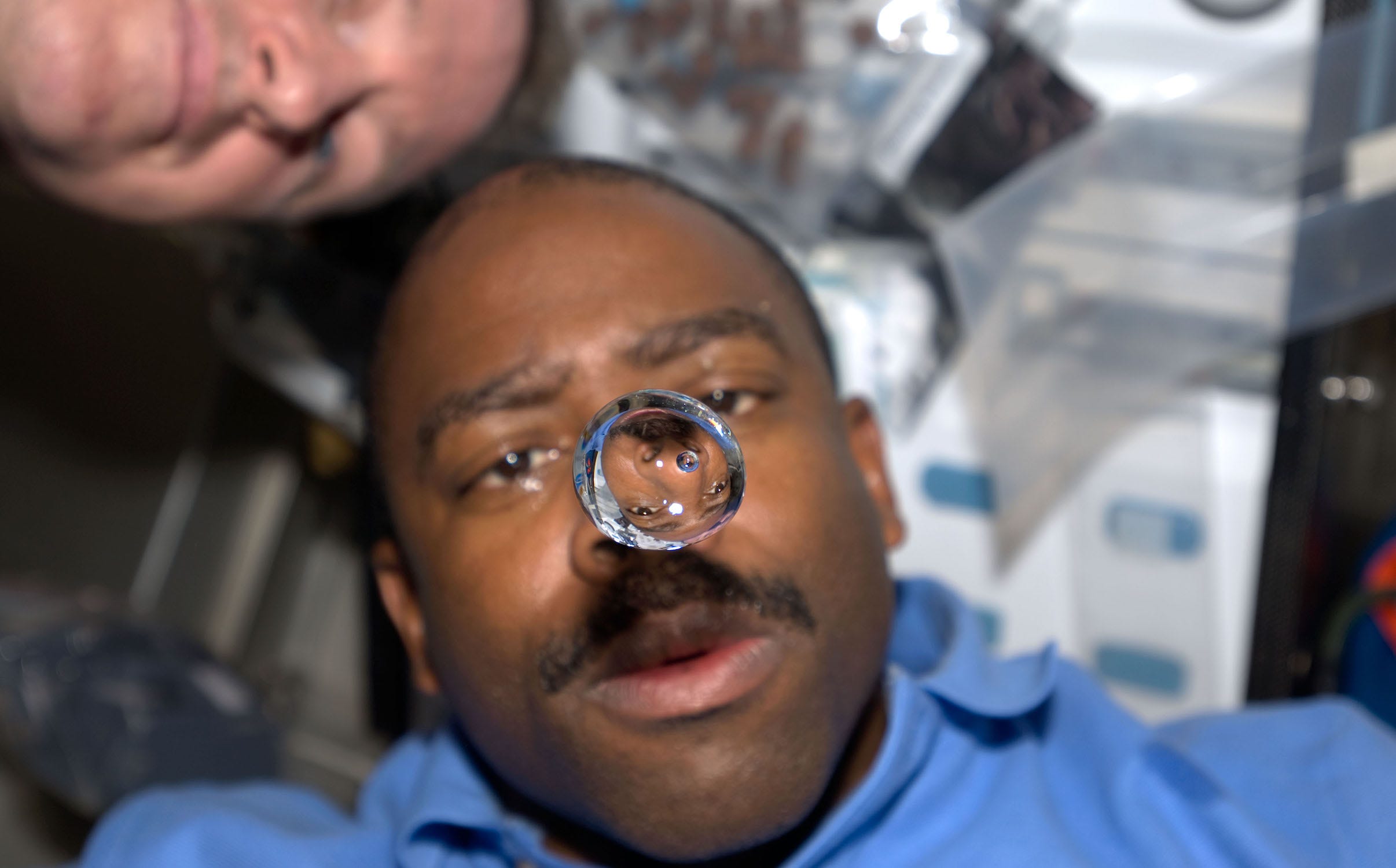 Eine Wasserblase schwebt vor NASA Leland Melvin im Space Shuttle Atlantis
