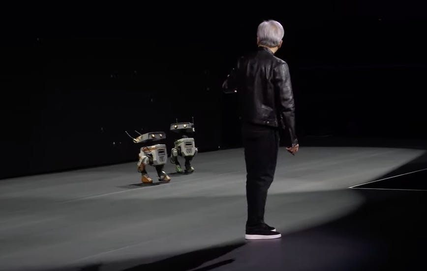 Jensen Huang betrachtet zwei Roboter auf der Bühne des Nvidia GTC.