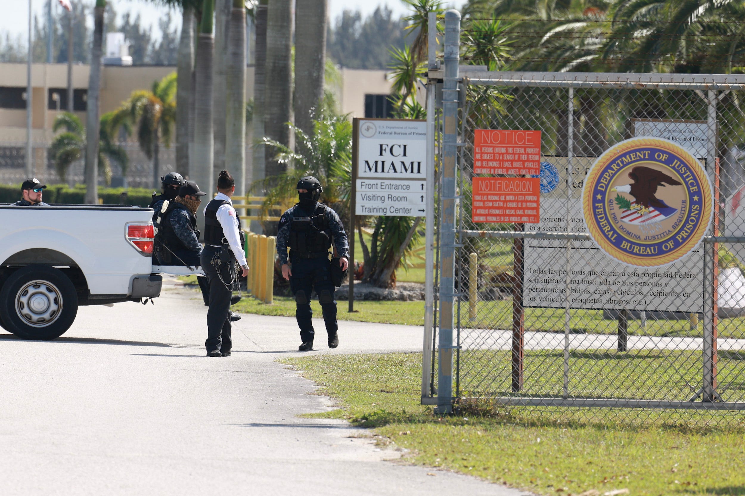 Sicherheitspersonal steht in der Nähe eines Drahtzauns Wache.  Auf einem weißen Schild steht FCI Miami