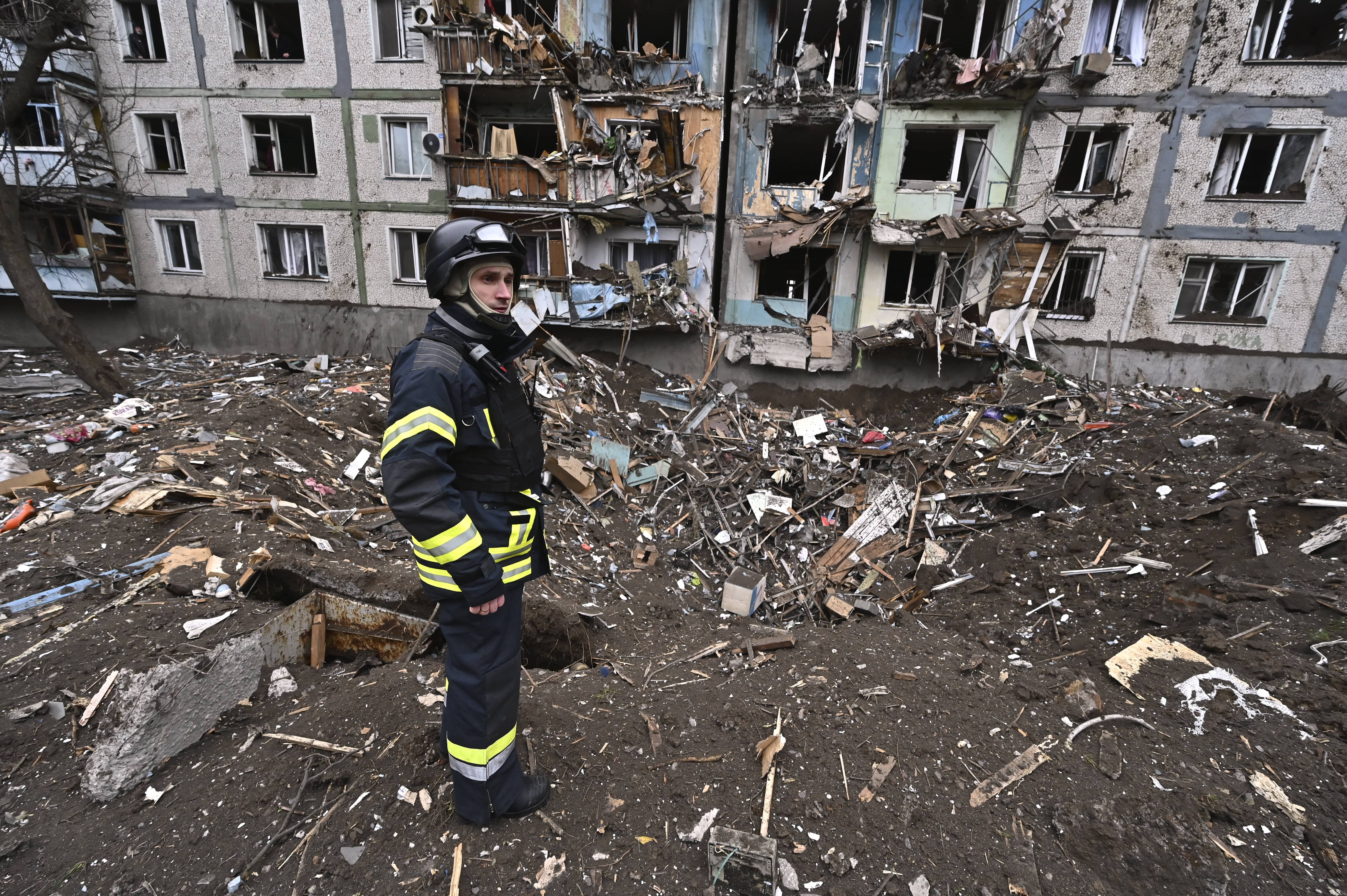 Ein Retter steht zwischen den Trümmern vor einem mehrstöckigen Wohngebäude, das am 22. März 2024 in Saporischschja, Ukraine, durch einen massiven Raketenangriff russischer Truppen beschädigt wurde.