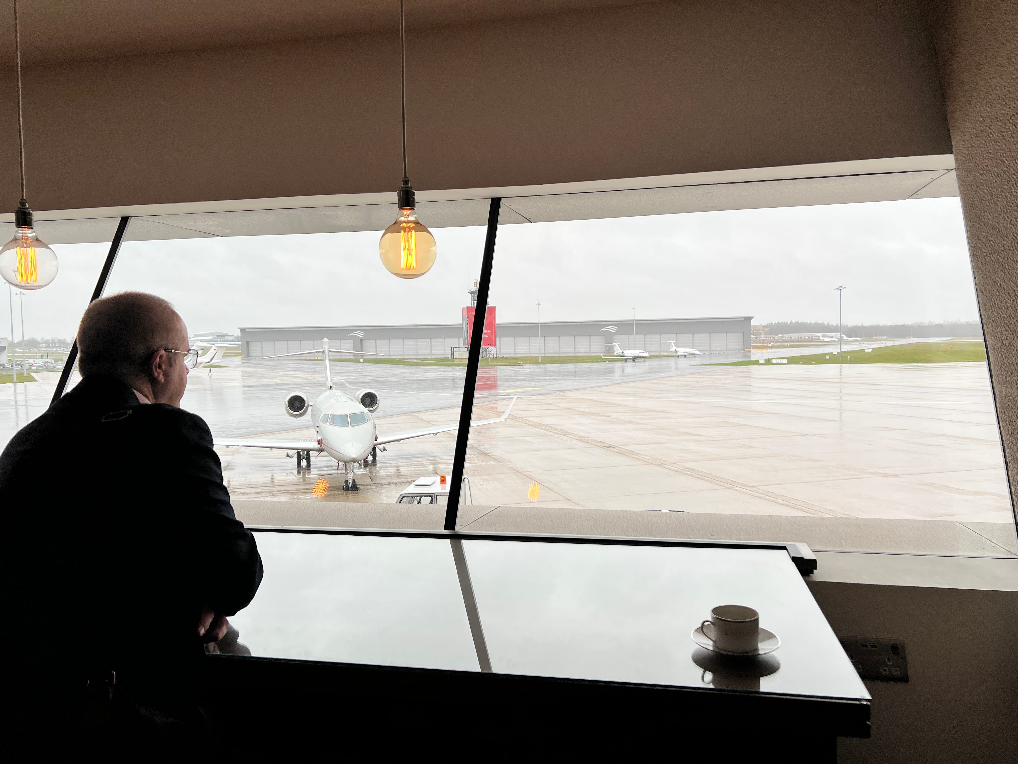 Ein Mann blickt am Flughafen Farnborough aus dem Fenster, im Vordergrund eine Challenger 300.