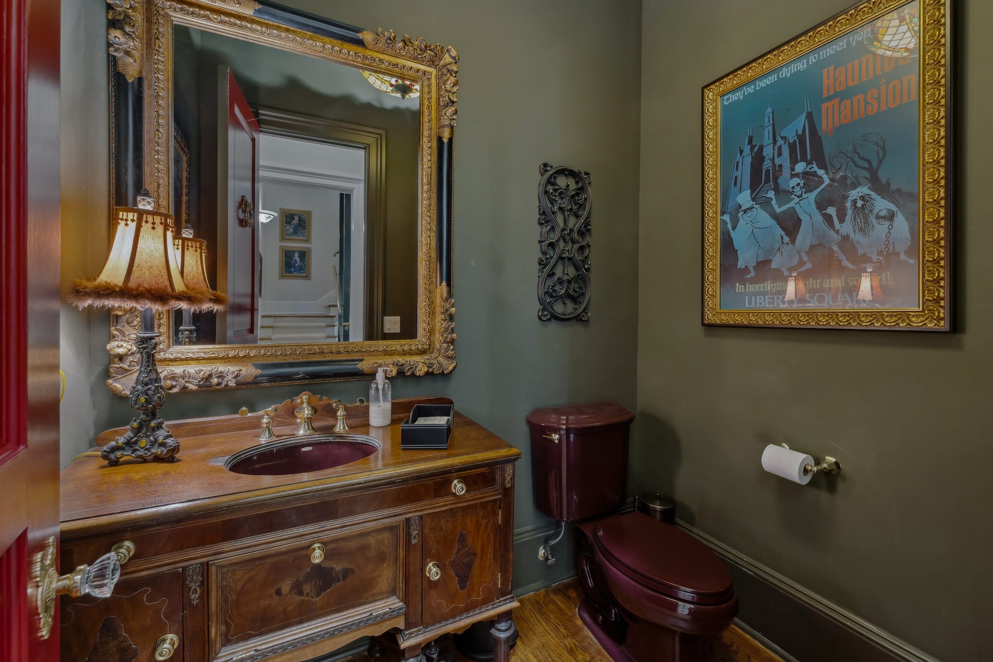Ein dunkelgrünes Badezimmer mit einem „Haunted Mansion“-Poster.