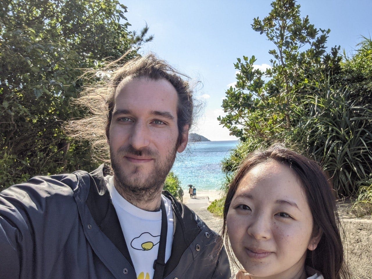 Ein Franzose und eine Japanerin machen ein Selfie am Strand.
