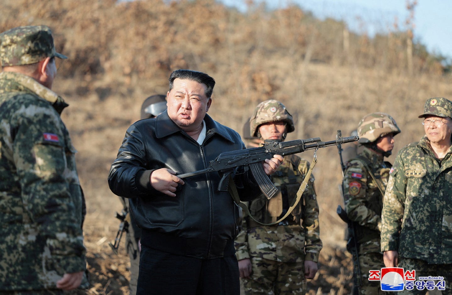Der nordkoreanische Führer Kim Jong Un hält eine Schusswaffe in der Hand, umgeben von Militärangehörigen
