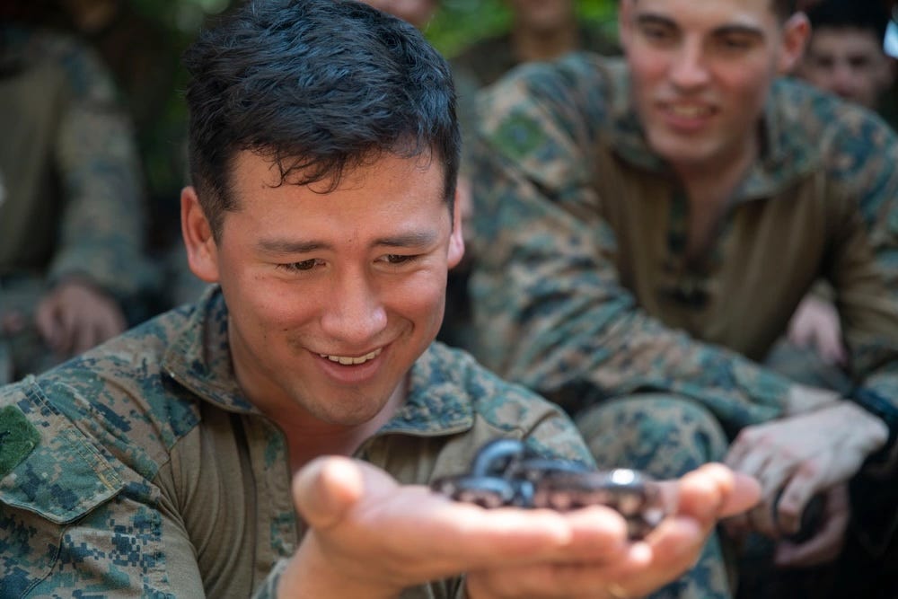 Ein US-Marine hält eine Schlange in seinen Händen