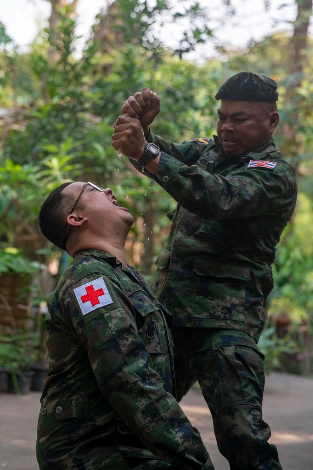 Ein Ausbilder der Royal Thai Marine drückt einem Marineinfanteristen Wasser aus einer Pflanze ins Maul