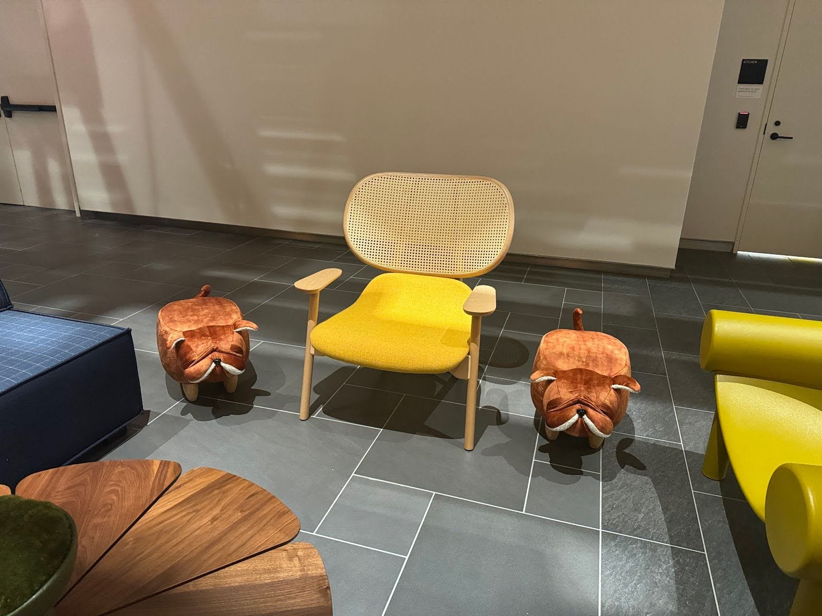 Ein gelber Stuhl mit zwei Hockern in Form von Bulldoggen auf beiden Seiten