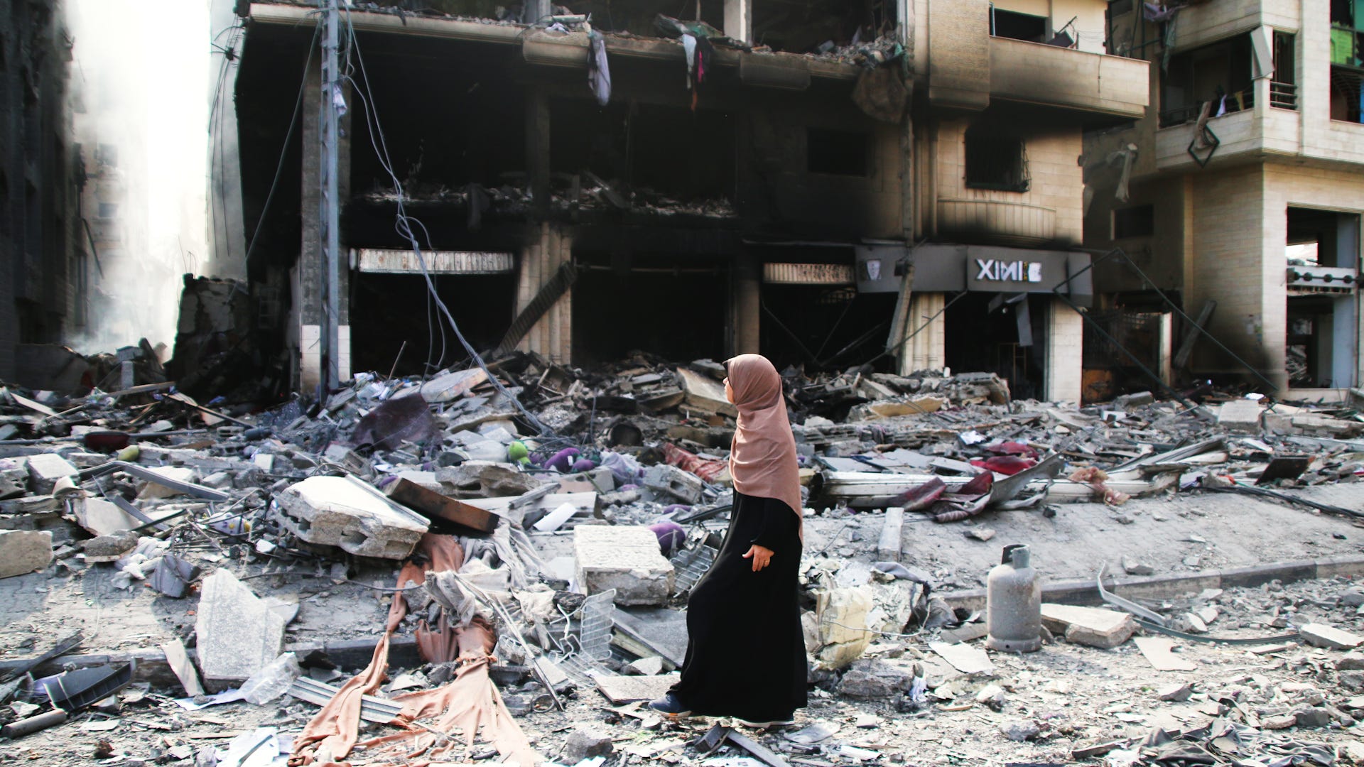 Eine Palästinenserin geht am 10. Oktober 2023 in Gaza-Stadt, Gaza, an durch israelische Luftangriffe beschädigten Gebäuden vorbei.