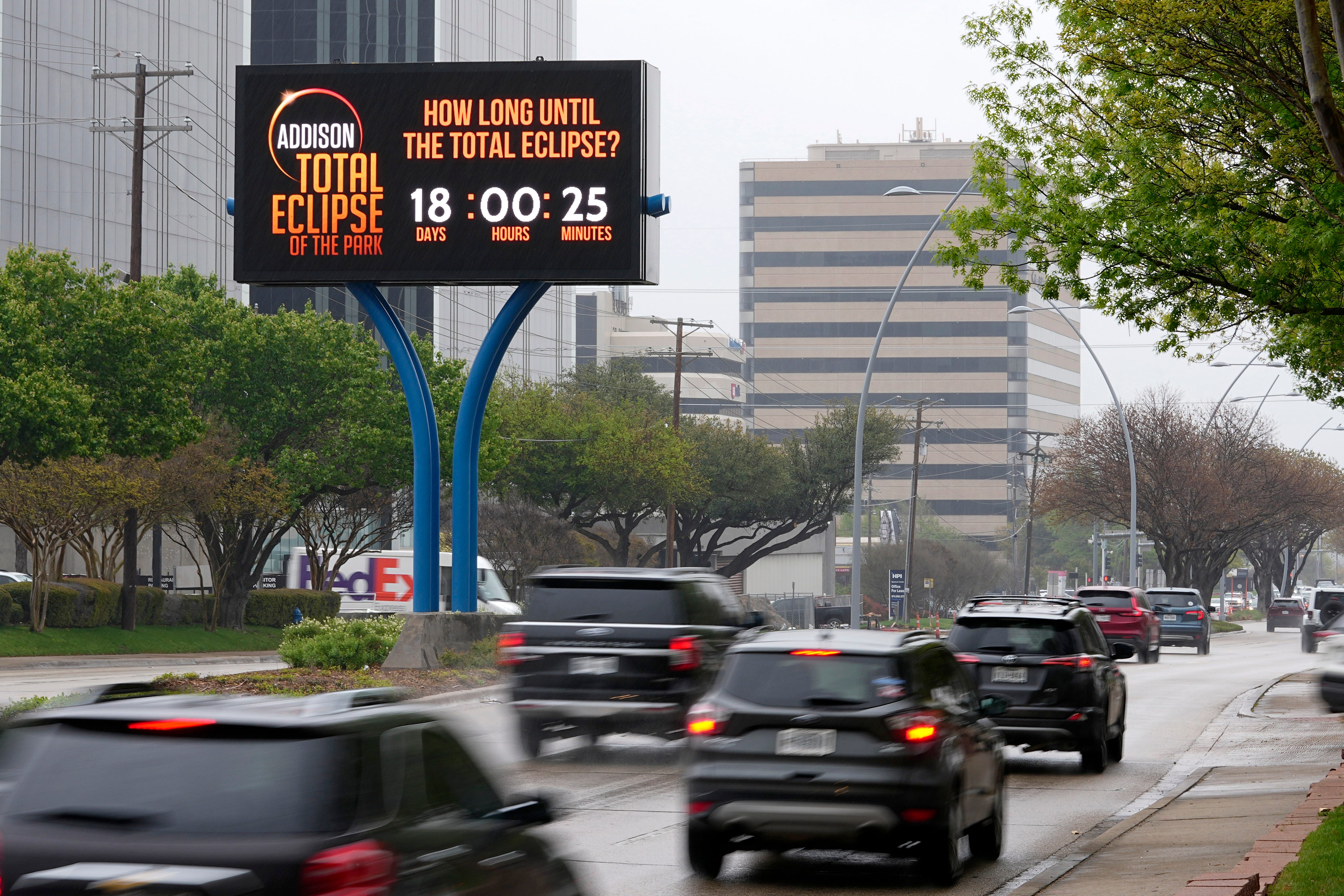 Informationen zur totalen Sonnenfinsternis werden auf einer digitalen Werbetafel angezeigt, während Autofahrer am Donnerstag, 21. März 2024, eine stark befahrene Straße in Addison, Texas, entlangfahren