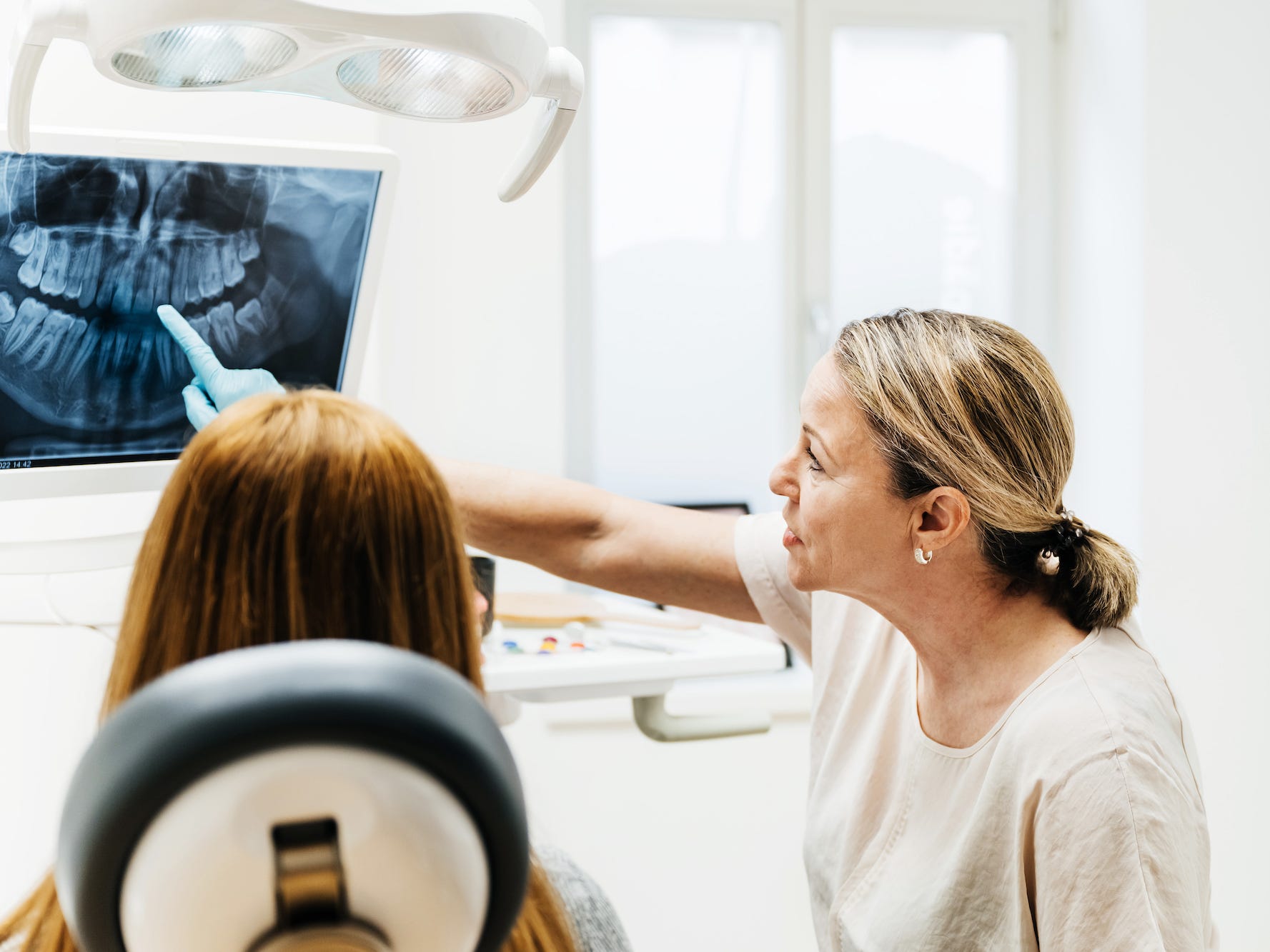 Kieferorthopäde und Patient betrachten eine Röntgenaufnahme der Zähne