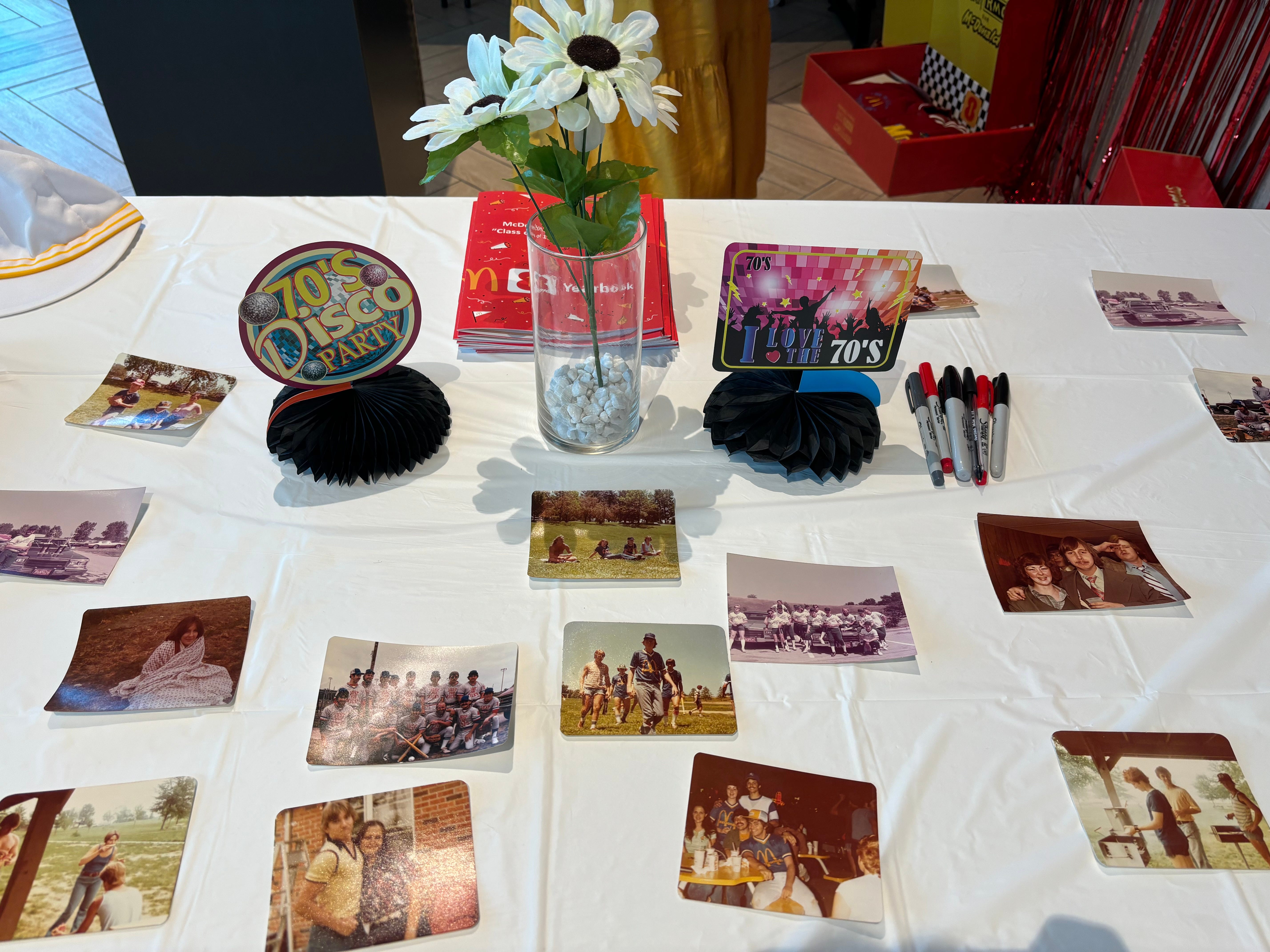 Ein Tisch, dekoriert mit Fotos ehemaliger McDonald's-Mitarbeiter und Gegenständen aus den 70er Jahren