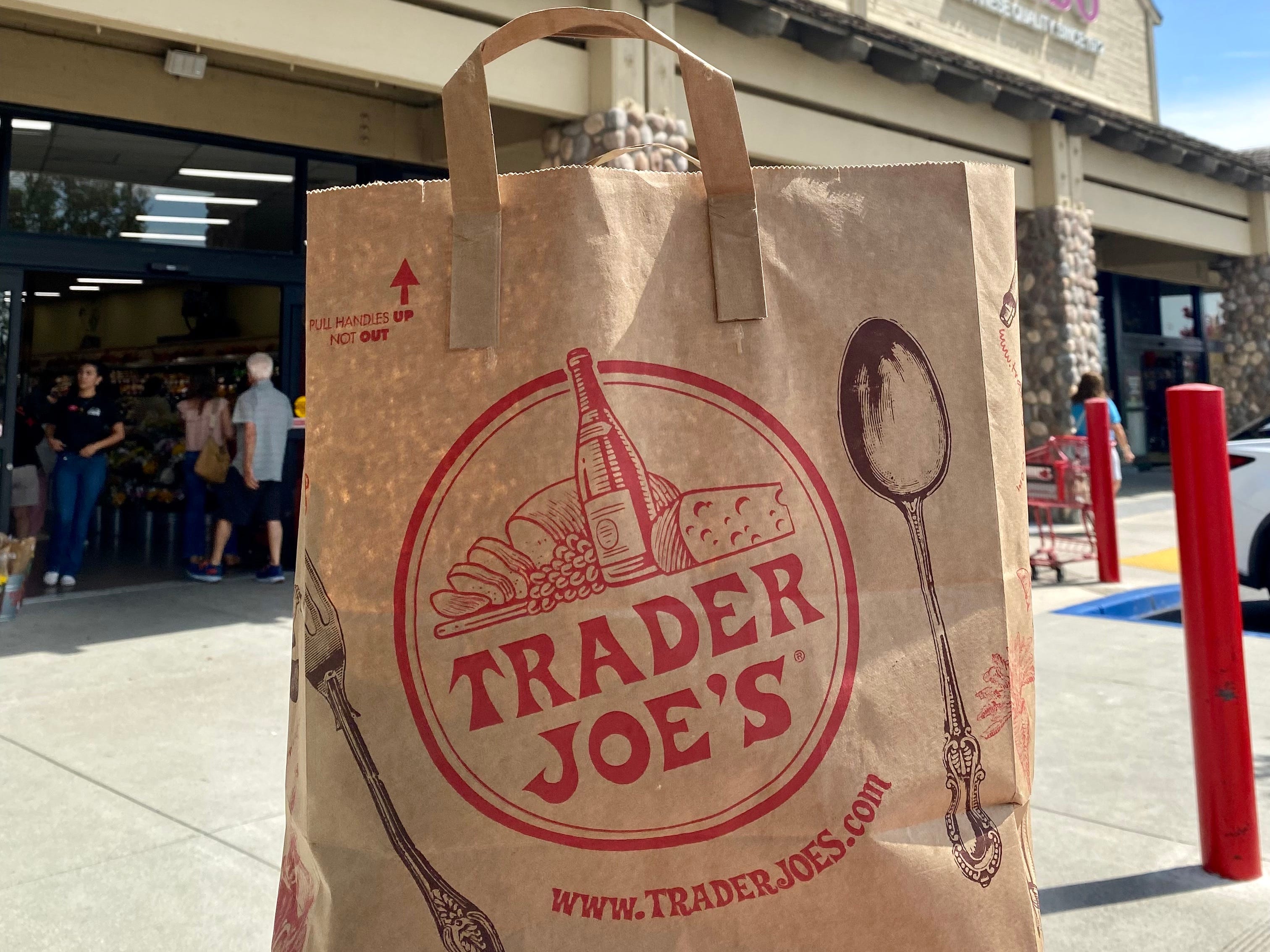 Die Tasche von Trader Joe vor dem Schild des Lebensmittelladens von Trader Joe.
