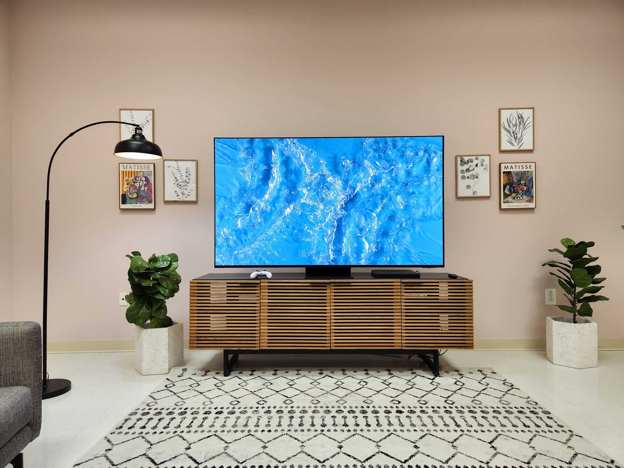 Ein Samsung S95D-Fernseher in einem Wohnzimmer mit einem Video von plätscherndem Wasser auf dem Bildschirm.
