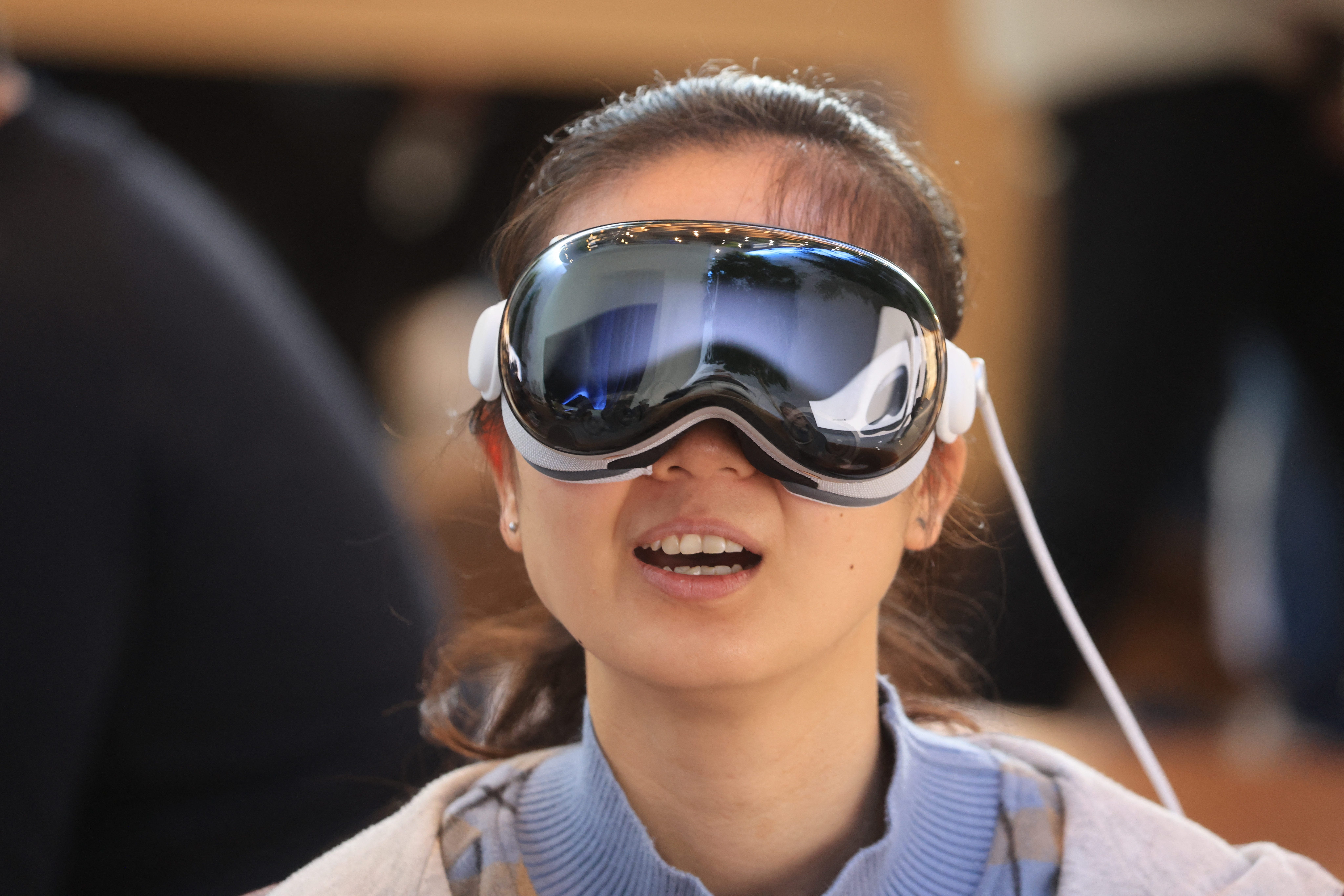Eine junge Frau probiert ein Apple Vision Pro-Headset an.