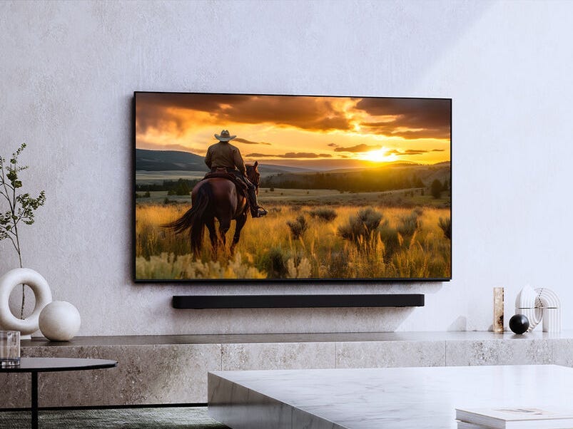 An der Wand hängt ein Sony Bravia 9-Fernseher, auf dem ein Mann auf einem Pferd zu sehen ist, der den Sonnenuntergang betrachtet.
