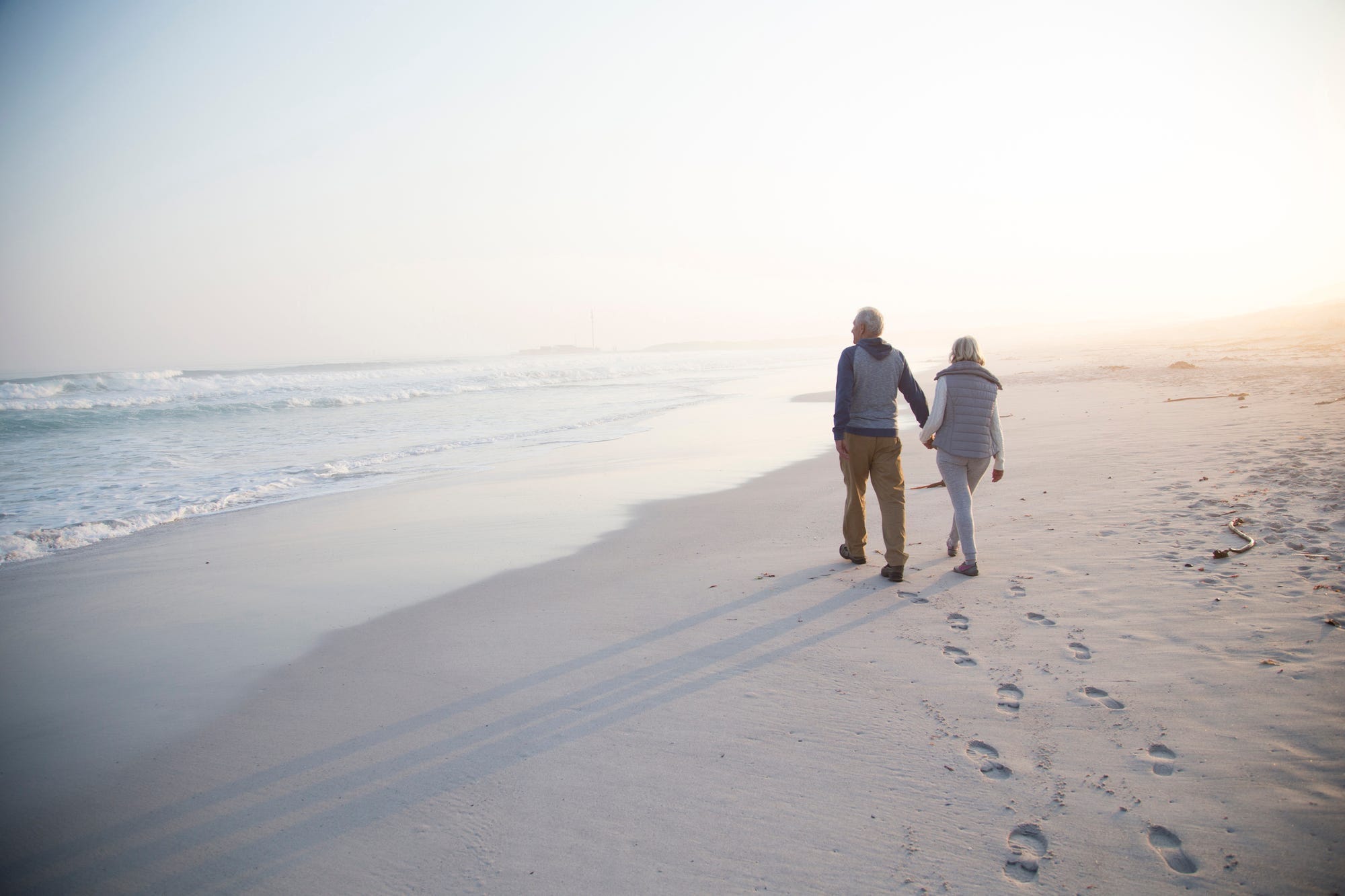 Ein älteres Paar spaziert am Strand entlang.