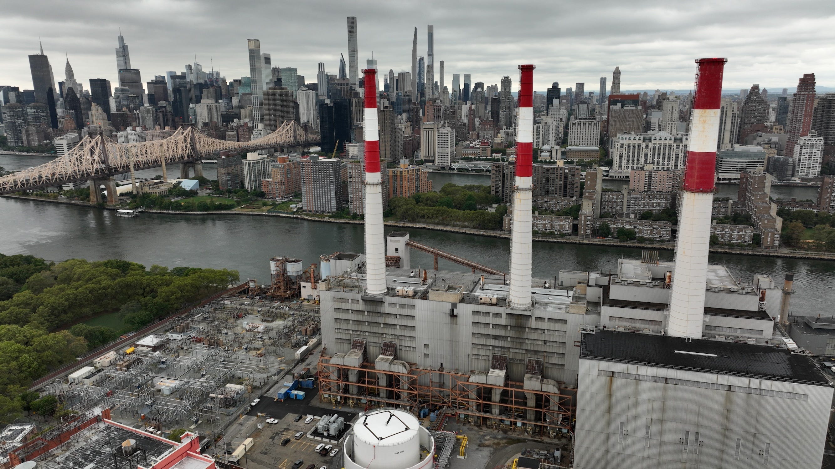 Rote und weiße Türme erheben sich aus einem Kraftwerk in New York City mit Gebäuden im Hintergrund