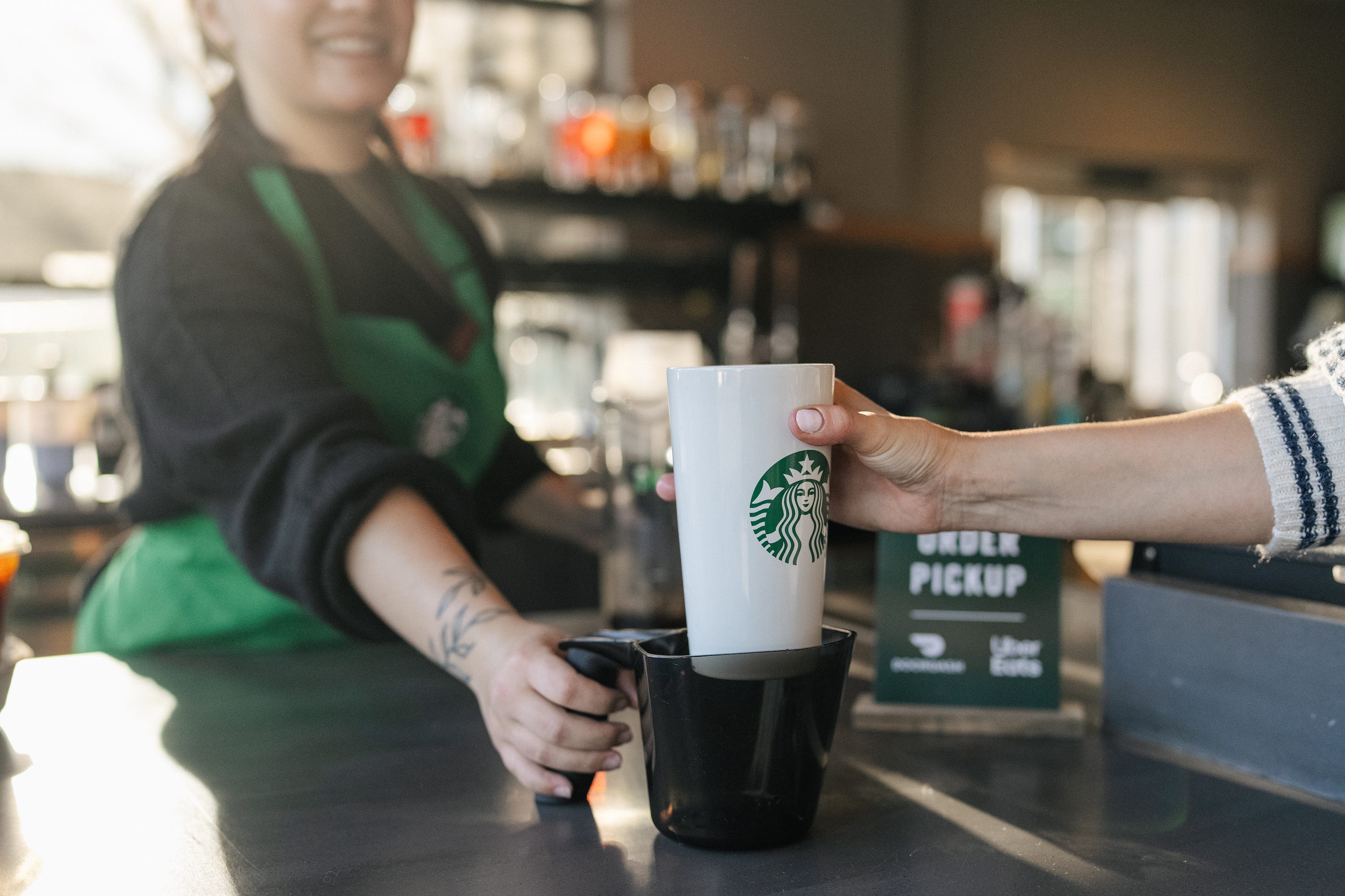 Ein Starbucks-Barista reicht einen wiederverwendbaren Getränkebecher aus