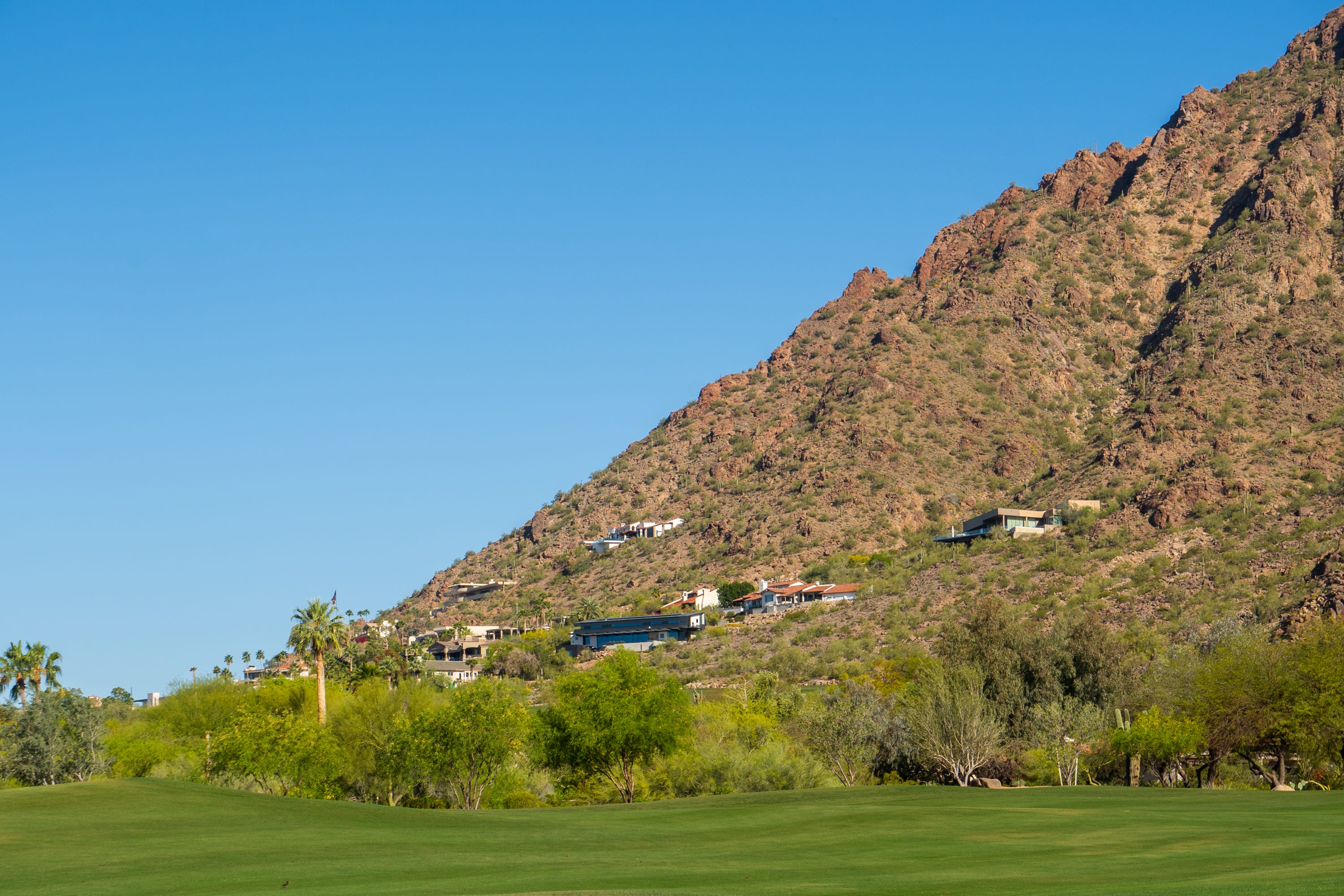 Millionärshäuser auf einem Berg über einem Golfplatz in Paradise Valley, Arizona, an einem Tag mit blauem Himmel