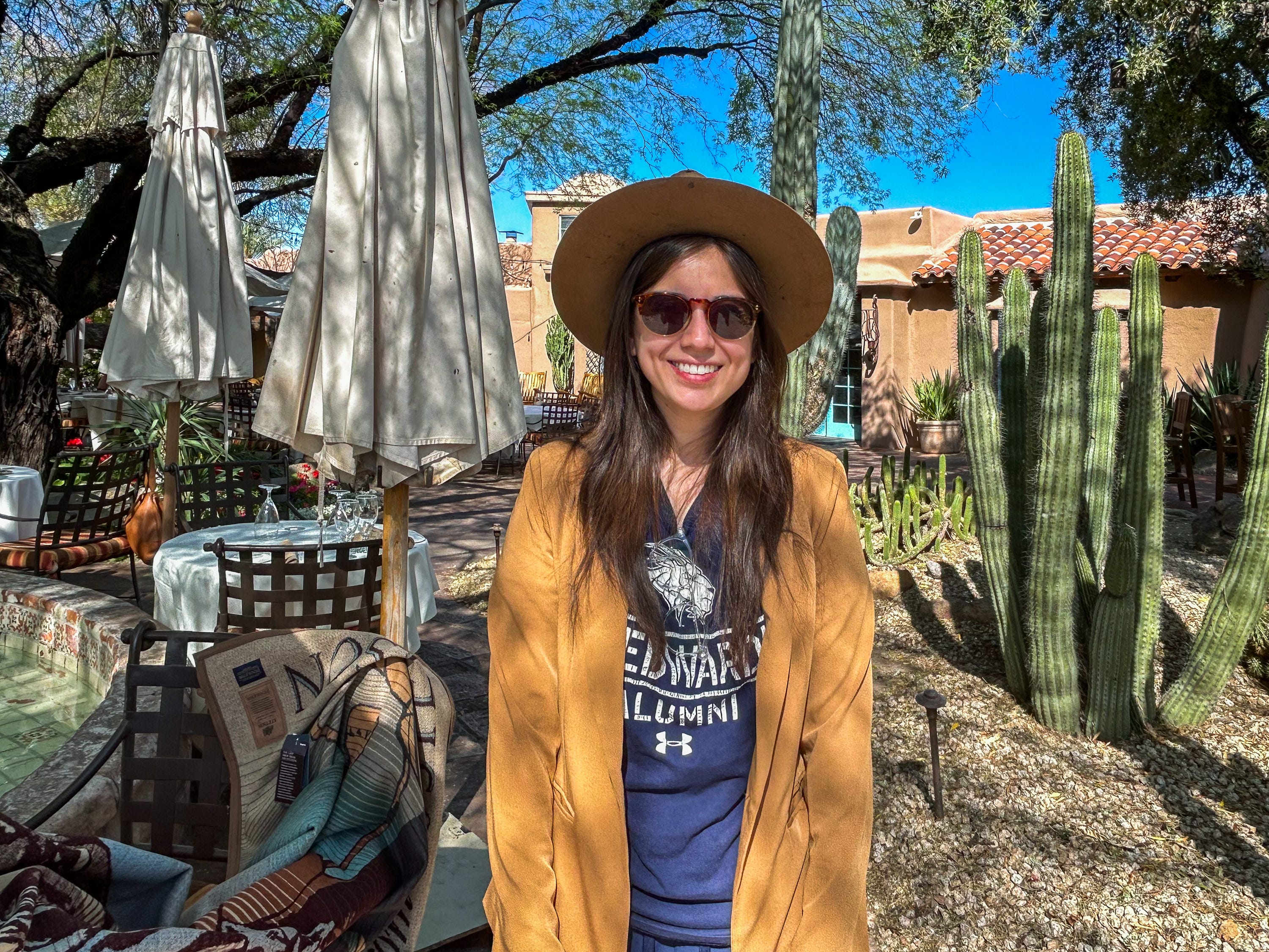 Der Autor mit Cowboyhut und Sonnenbrille steht lächelnd vor Kakteen und einem Lehmgebäude in Scottsdale
