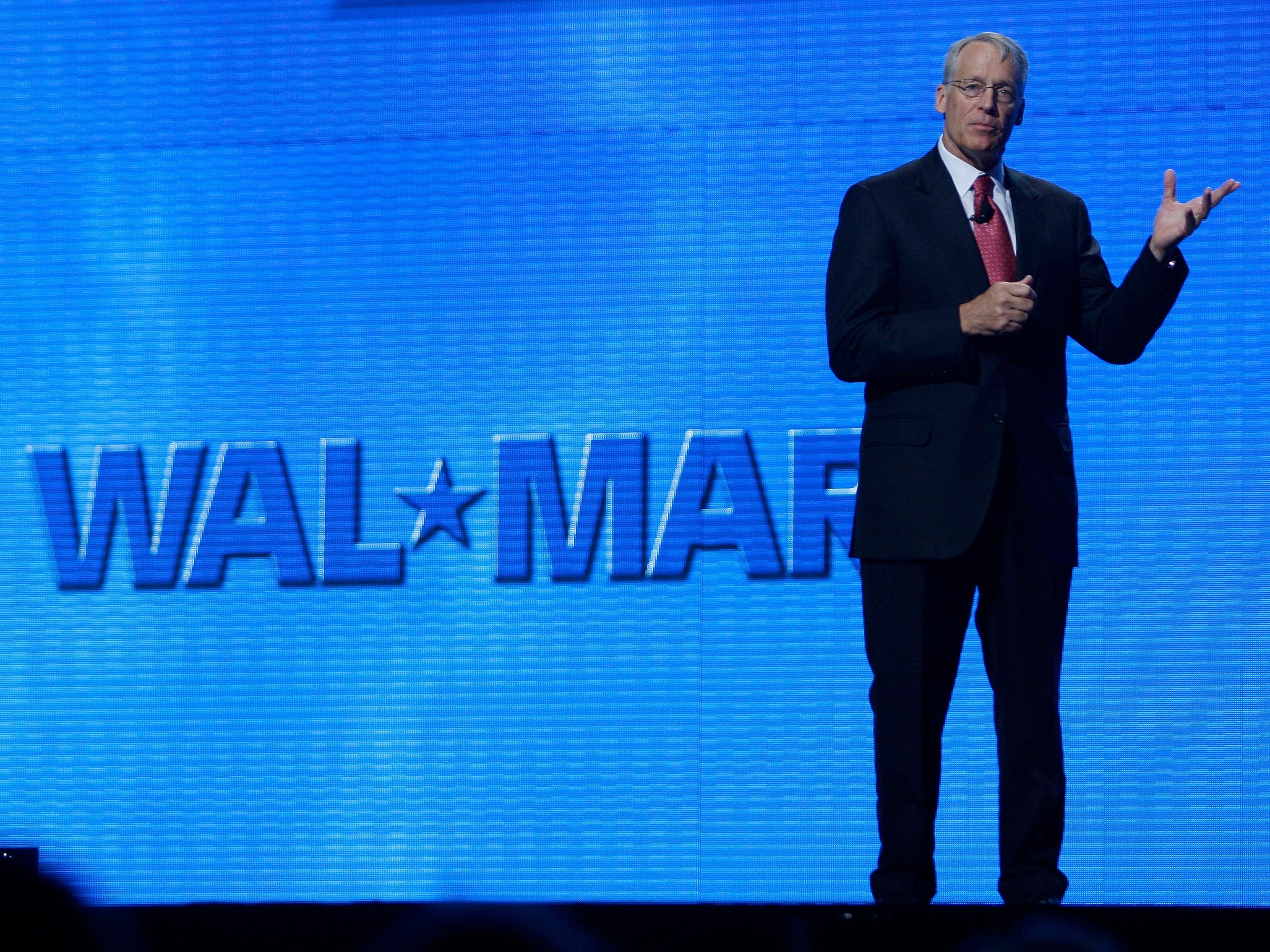 Rob Walton gestikuliert auf der Bühne vor dem blauen Walmart-Logo