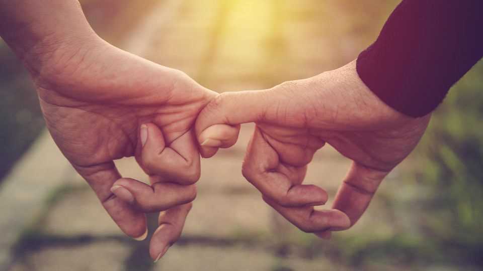 7 clear signs of love: man and woman hold each other's little fingers