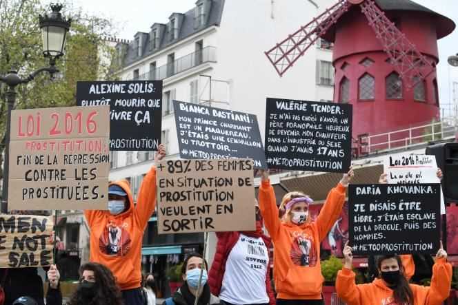 Sex workers, some of whom are holding signs, gather in front of the Moulin-Rouge cabaret to demand the application of the French law of 2016 on prostitution, in Paris, Sunday April 11, 2021.