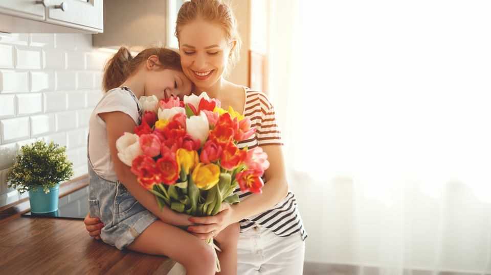 Why do we celebrate Mother's Day?  Daughter presents bouquet of flowers to mom