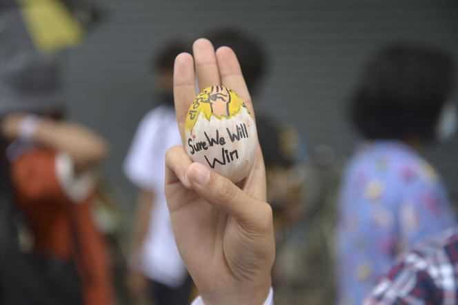 A protester lifts an Easter egg, decorated with the three-fingered resistance symbol, during a demonstration against the military coup on Easter Sunday, April 4 in Yangon.