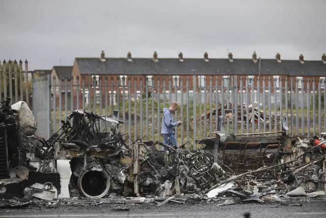 A passerby in front of the hijacked and torched bus on Shankill Road, Belfast, April 7, 2021.