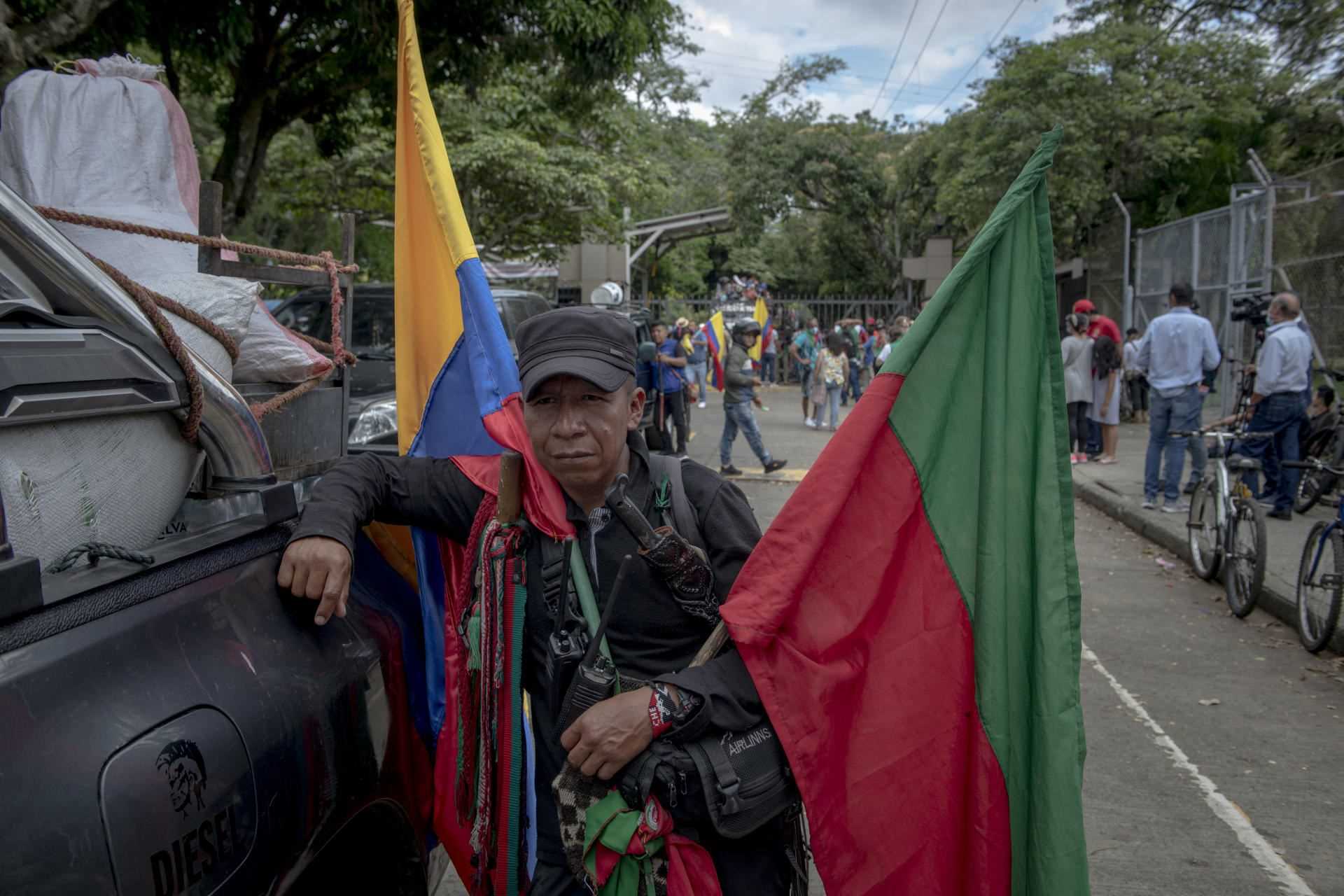 “Camayo”, indigenous guard of the minga, carries the Colombian flags and that of the indigenous organization CRIC.