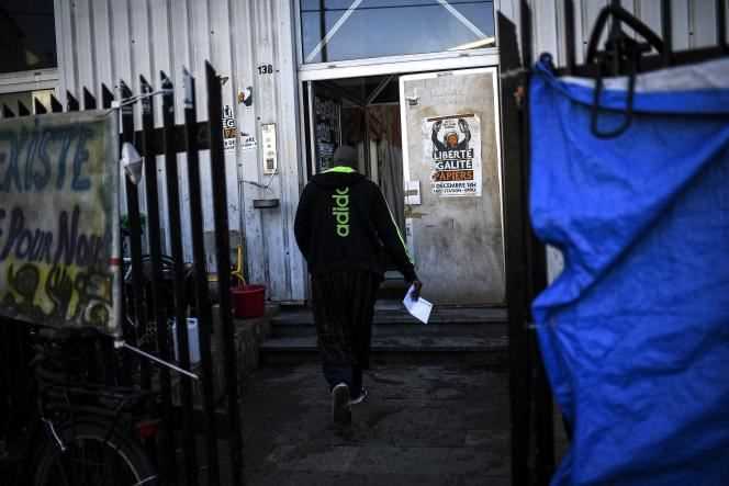 An African migrant enters a hangar transformed into a squat housing more than 200 men, mostly Malians, in Montreuil (Seine-Saint-Denis), February 24, 2021.