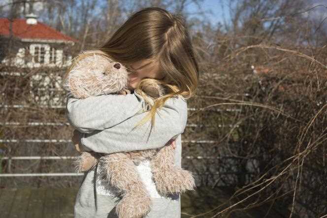 A little girl holds her teddy bear.