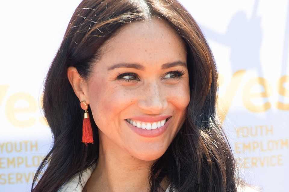 Duchess Meghan shines with coral-colored tassel earrings. 