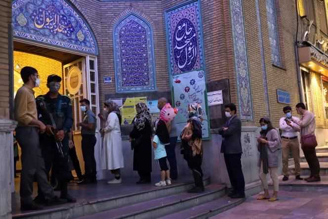Voters wait in front of a polling station in Tehran on June 18, 2021.