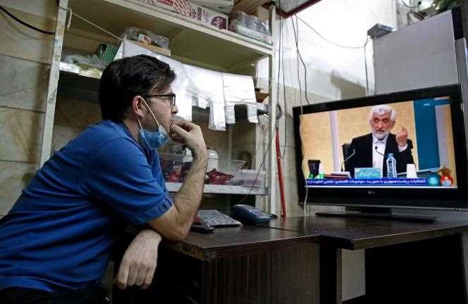 An Iranian watches the first televised presidential campaign debate on Saturday, June 5.