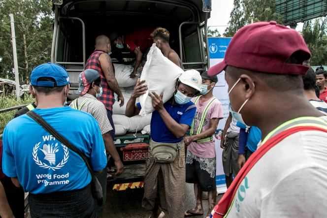 People receive bags of rice distributed by the World Food Program on the outskirts of Yangon, Burma, on May 21, 2021.