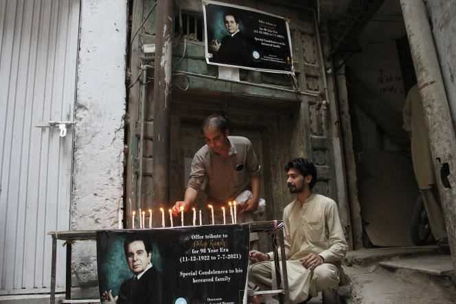 Local residents light candles next to a poster of Bollywood icon Dilip Kumar to pay tribute to him, outside the remains of his ancestral home, in Peshawar, Pakistan, Wednesday, July 7, 2021.