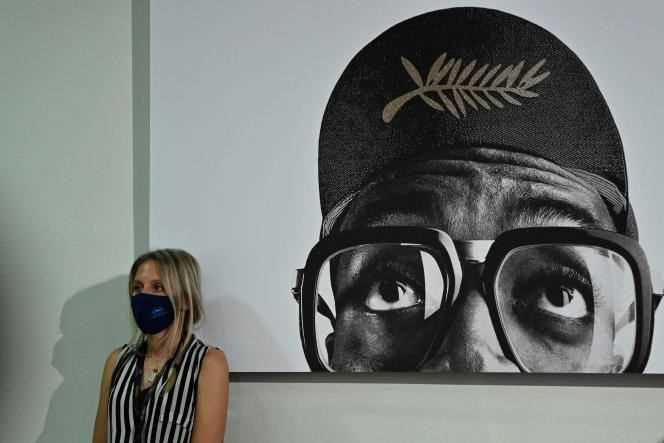 A masked journalist leaning against a poster of the 74th Cannes Film Festival, July 10, 2021.
