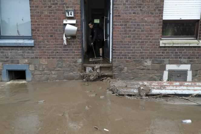 A woman sweeps up water from her flooded house, after heavy rains, in Trooz, Belgium, July 16, 2021.
