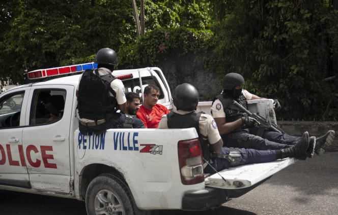 A police vehicle carries two suspects handcuffed and framed by police, Thursday, July 8, in Port-au-Prince.