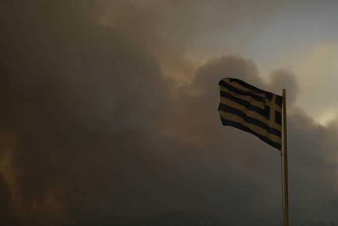 The Greek flag veiled by a thick cloud of smoke in Gouves, on the island of Evia, August 8, 2021.