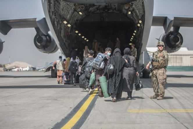 Afghan families board a US military plane to be evacuated from Afghanistan at Kabul airport in August 2021.