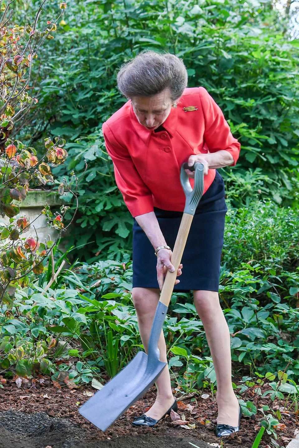 Princess Anne is in costume with a shovel in the garden.