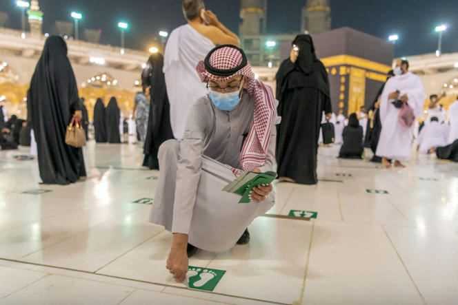 A photo released by the Saudi presidency shows officials removing signs of social distancing at the Grand Mosque in Mecca on October 17, 2021.