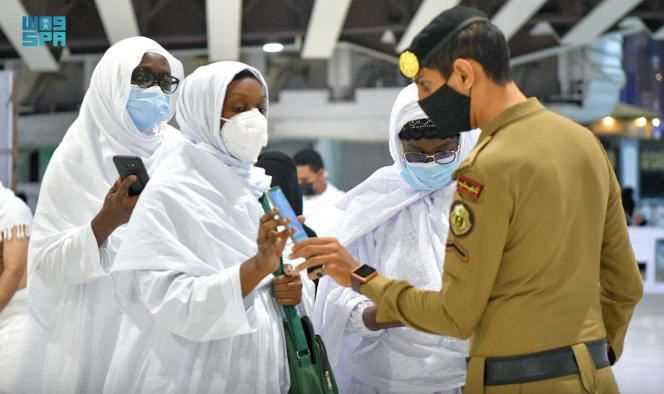 A member of the Saudi Arabian police checks the details of the pilgrims' vaccination on their smartphone, at the Grand Mosque, in the holy city of Mecca, Saudi Arabia, on October 17, 2021.