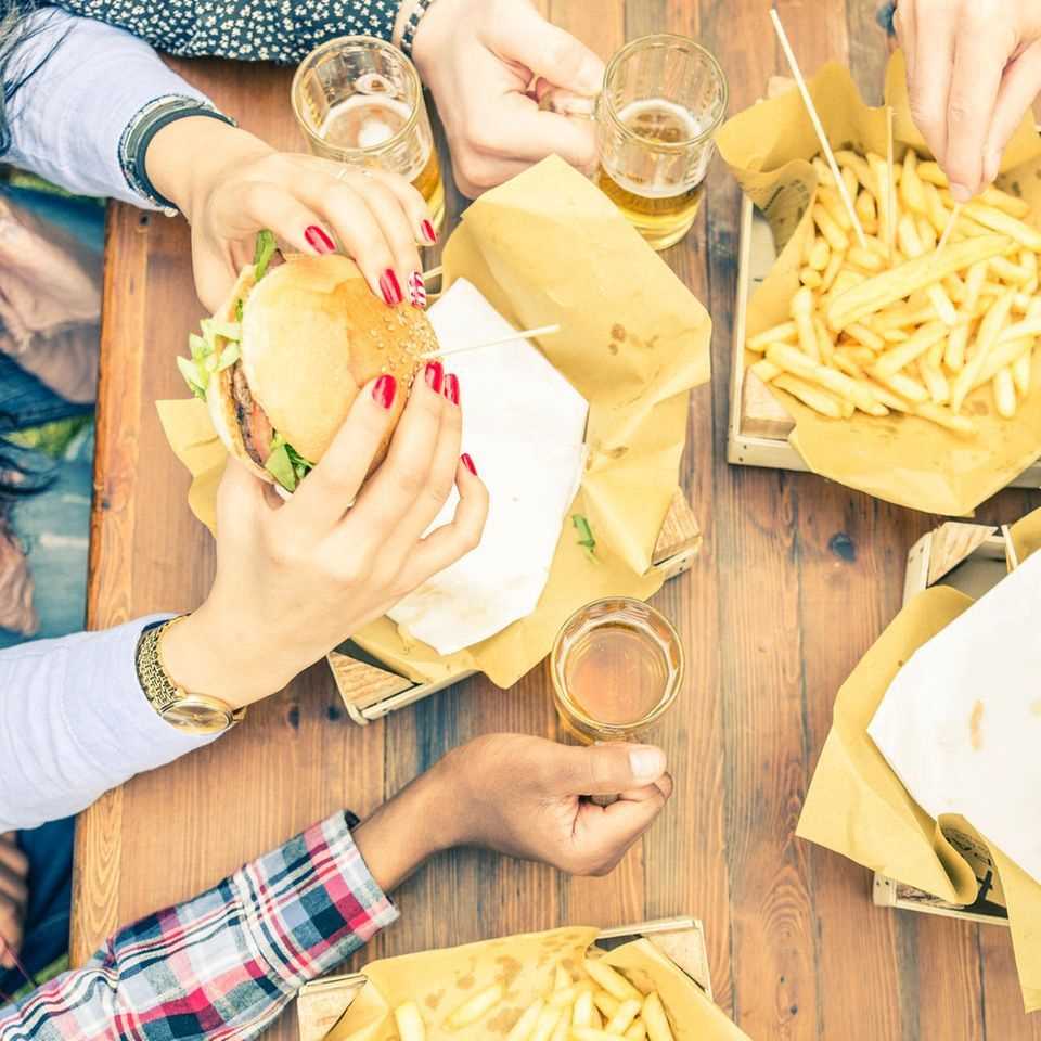 Inflammatory foods: people eat burgers with fries and drink beer.
