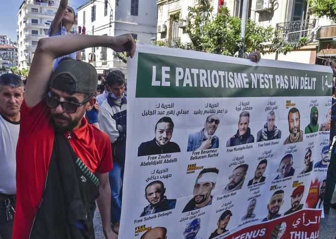 Anti-government protesters carry a poster of imprisoned activists in Algiers on May 7, 2021.