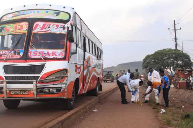 Ugandan police officers investigate the crime scene of the explosion on a bus, where at least one person died and several were injured, near Kampala on October 25, 2021.