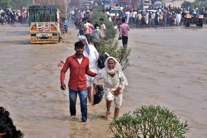 Residents of Rampur cross a flooded highway after the Kosi River flooded in the Indian state of Uttar Pradesh on October 20, 2021.